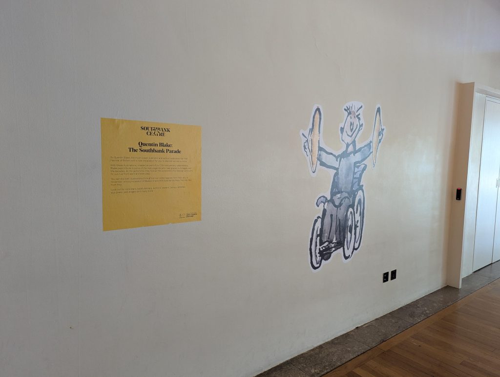 A Quentin Blake illustration of a person in a wheelchair, holding cymbals, pasted on a wall.