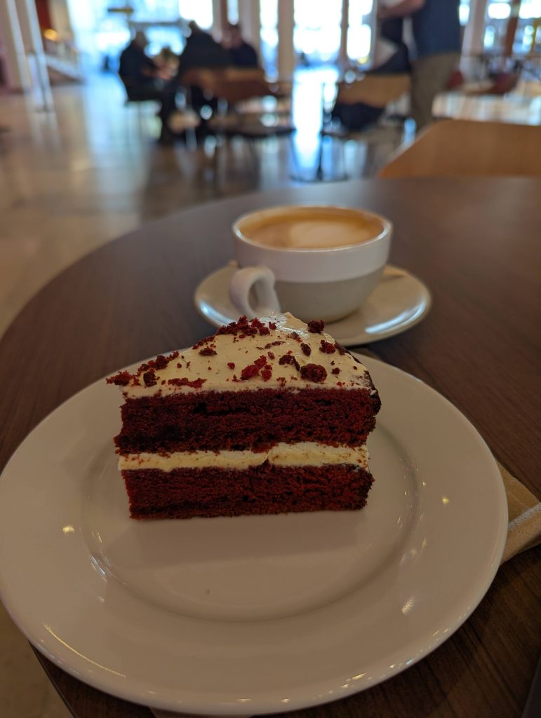 A slice of cake and a coffee on a table.