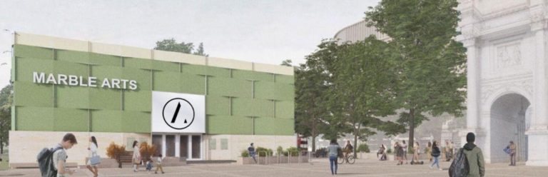 A picture of a modern green building with the label Marble Arts on it. It is surrounded by trees and people walking.