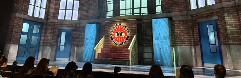 a stage which is set up like an American high school and features a big school sign reading Westerberg High School.